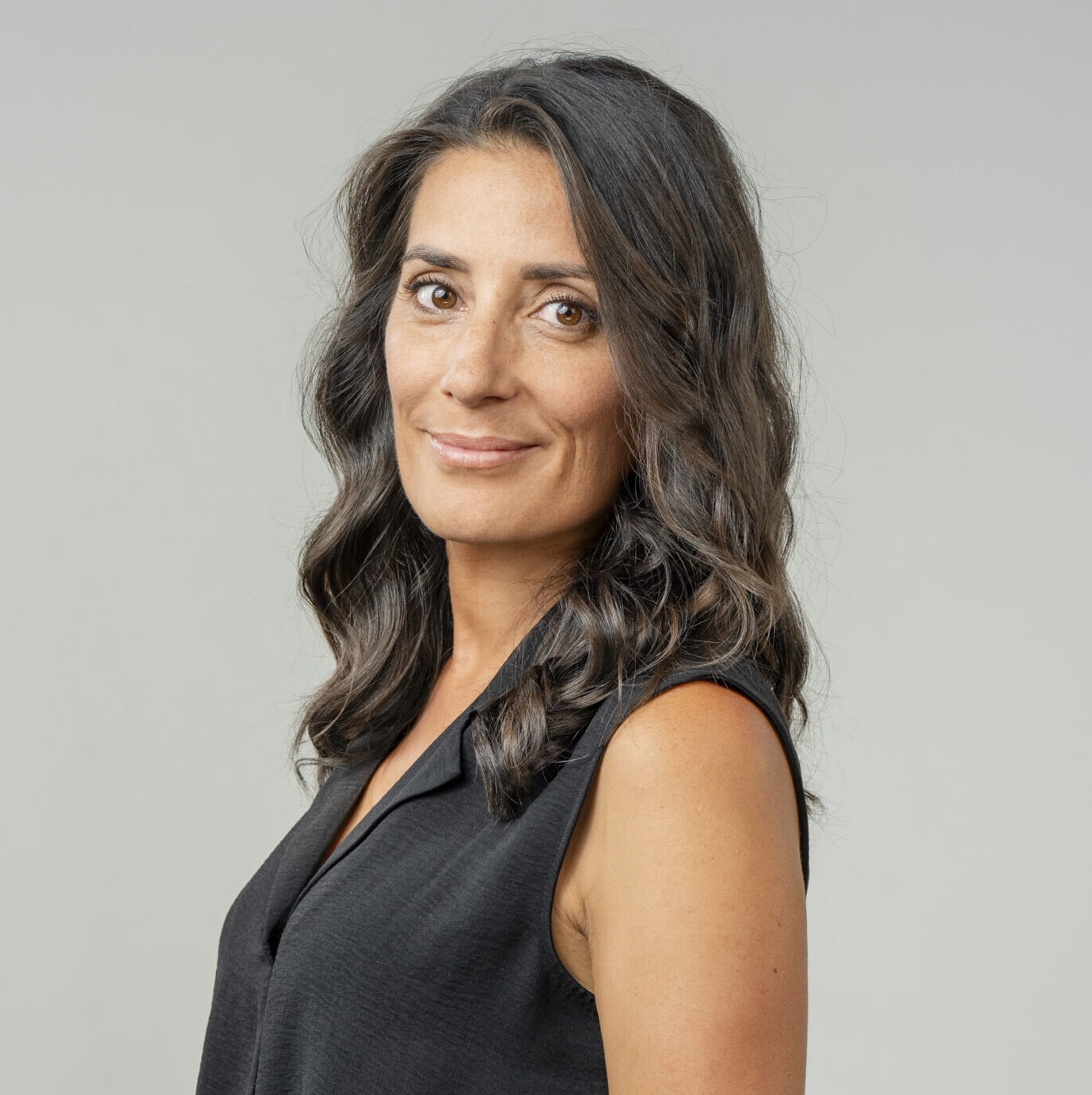 Un portrait de profil d’une femme portant un pull à col roulé ocre et un sac blanc. Elle regarde en l’air et ferme les yeux.